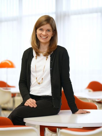 Alexandra Krau&szlig; sitzt auf einem Tisch in Club Orange und l&auml;chelt in die Kamera.